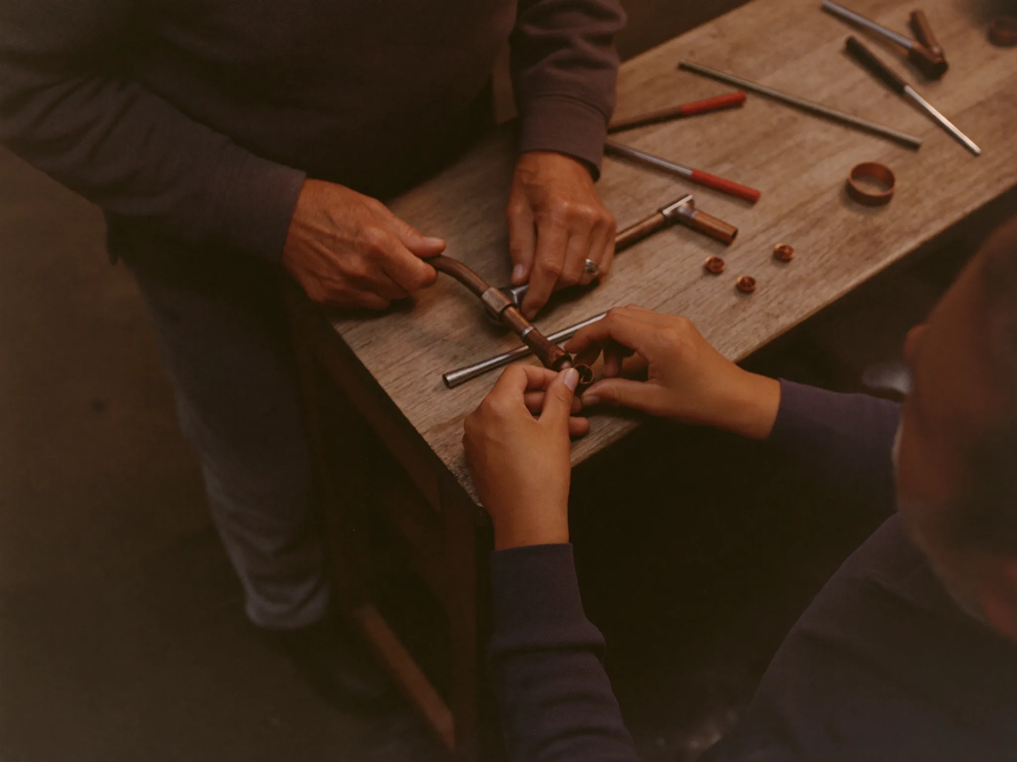 Zwei Handwerker an der Werkbank, eine Rohrverbindung wird gezeigt